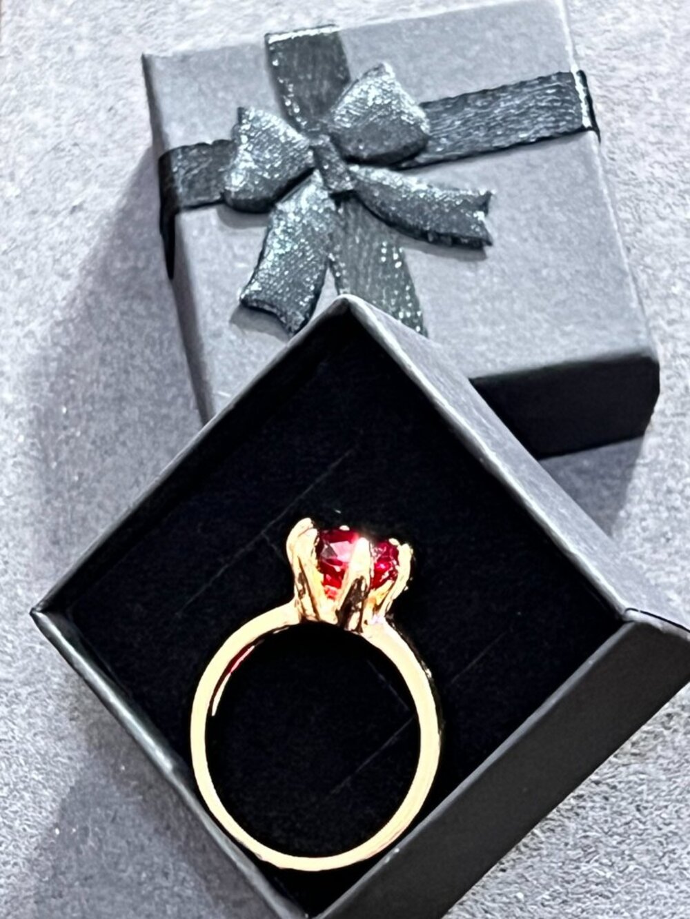 Elegant gold-tone solitaire-style ring featuring a faceted red stone in a
